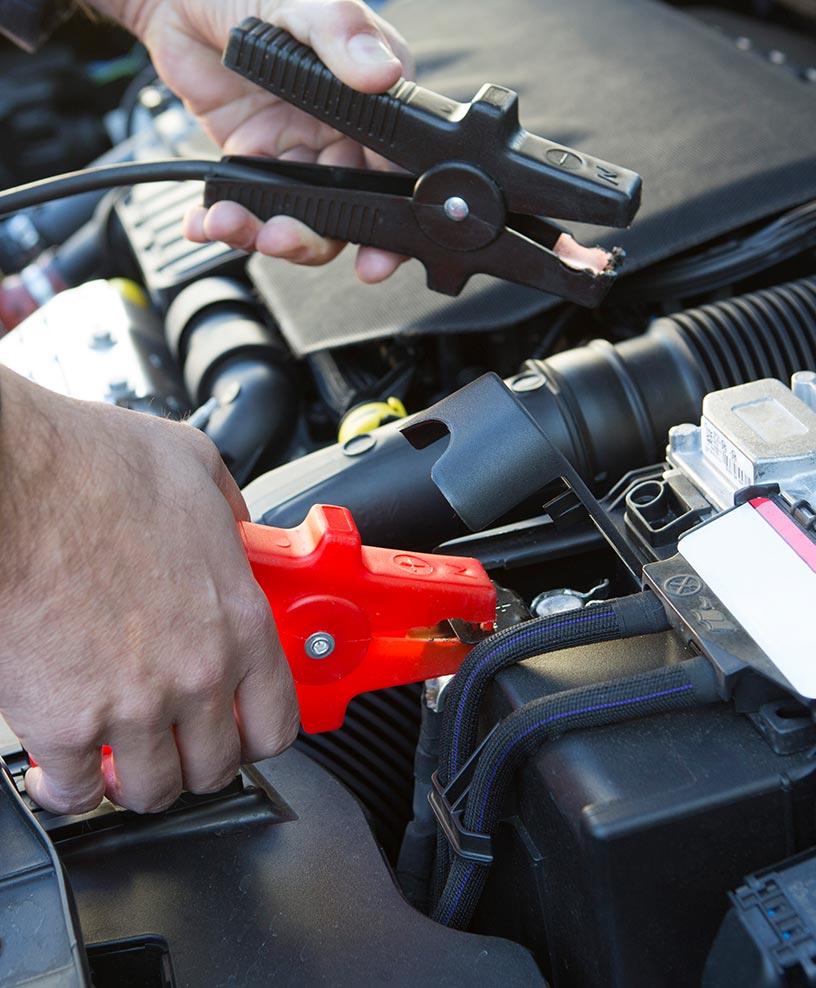 Technician connecting jumper cables to a car battery